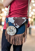 Fixation Fibre and Function denim crossbody bag with cowhide flap, fringe, and jeweled flower accent on a person